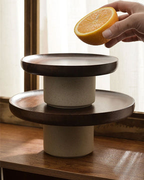 The Wooden Cake Stand displayed with a selection of fruits, demonstrating its versatility and the warm, rustic charm it brings to table settings.