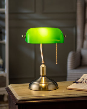 Illuminated Electric table lamp that has a brass stand, a green glass lamp shade and a pull-chain switch.