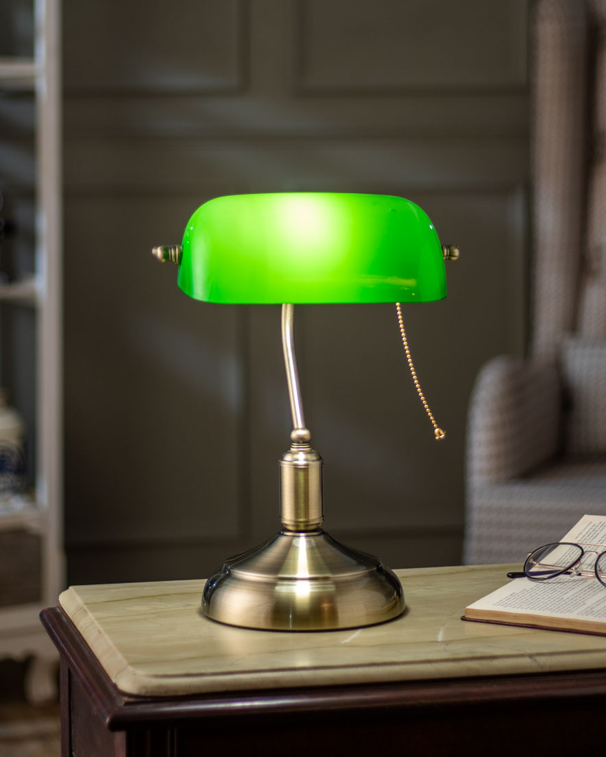 lighted Electric table lamp that has a brass stand, a green glass lamp shade and a pull-chain switch.