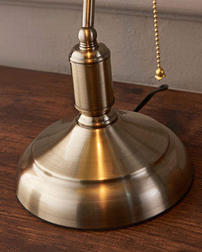 Retro green-shaded Banker's Lamp illuminating a wooden desk with brass accents.