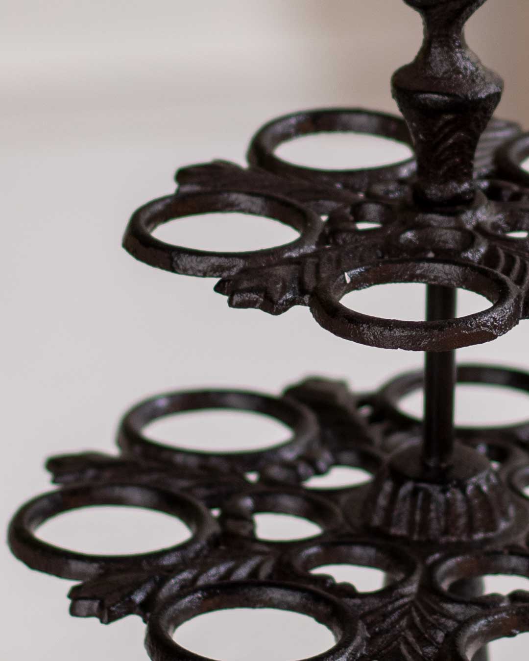 Elegant wall-mounted cast iron bird feeder with decorative birds, affixed to a pale-colored wall.