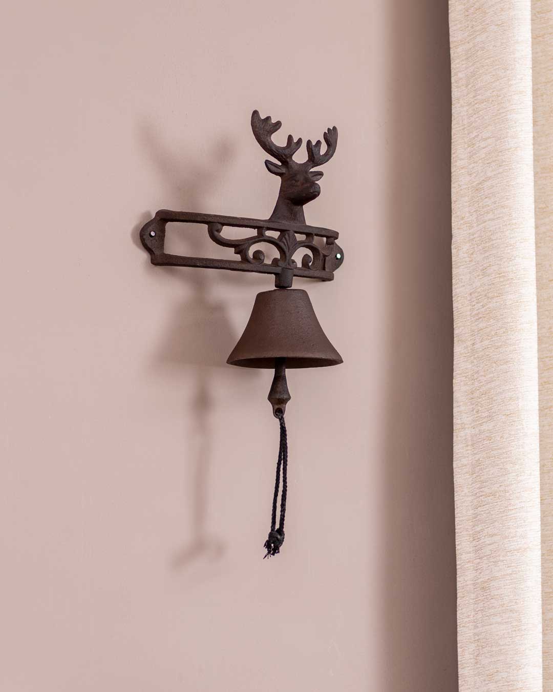Antique-style cast iron dinner bell with a decorative reindeer, perfect for wall mounting.