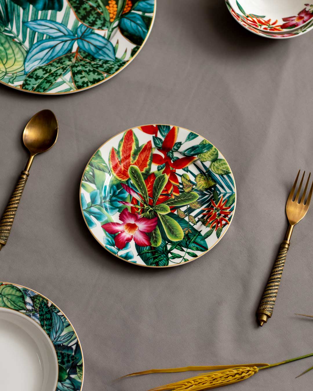 Leafy Elegance Quarter Plate with vibrant tropical leaf and flower design, accompanied by antique gold cutlery, on a muted grey background, perfect for a botanical-themed table setting.