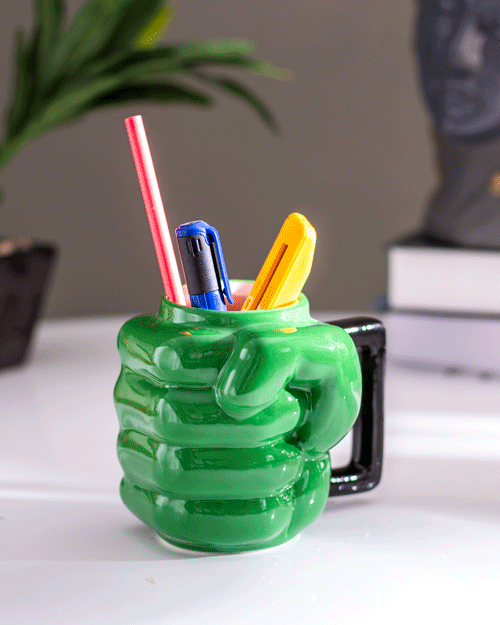 Funky 'Mighty Green Punch' coffee mug used as a pen holder, adding a pop of color to the workspace.