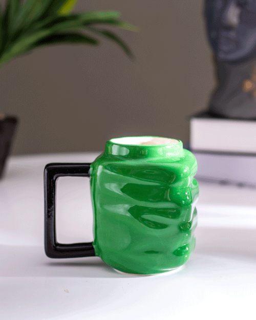 Creative green fist-shaped coffee mug with black handle, a quirky addition to any coffee lover's collection.