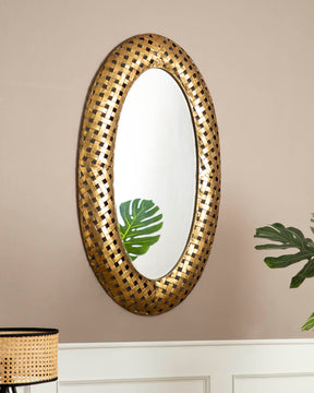 Darius oval wall mirror with a checkered golden frame, mounted on a beige wall, reflecting elegant home interiors.