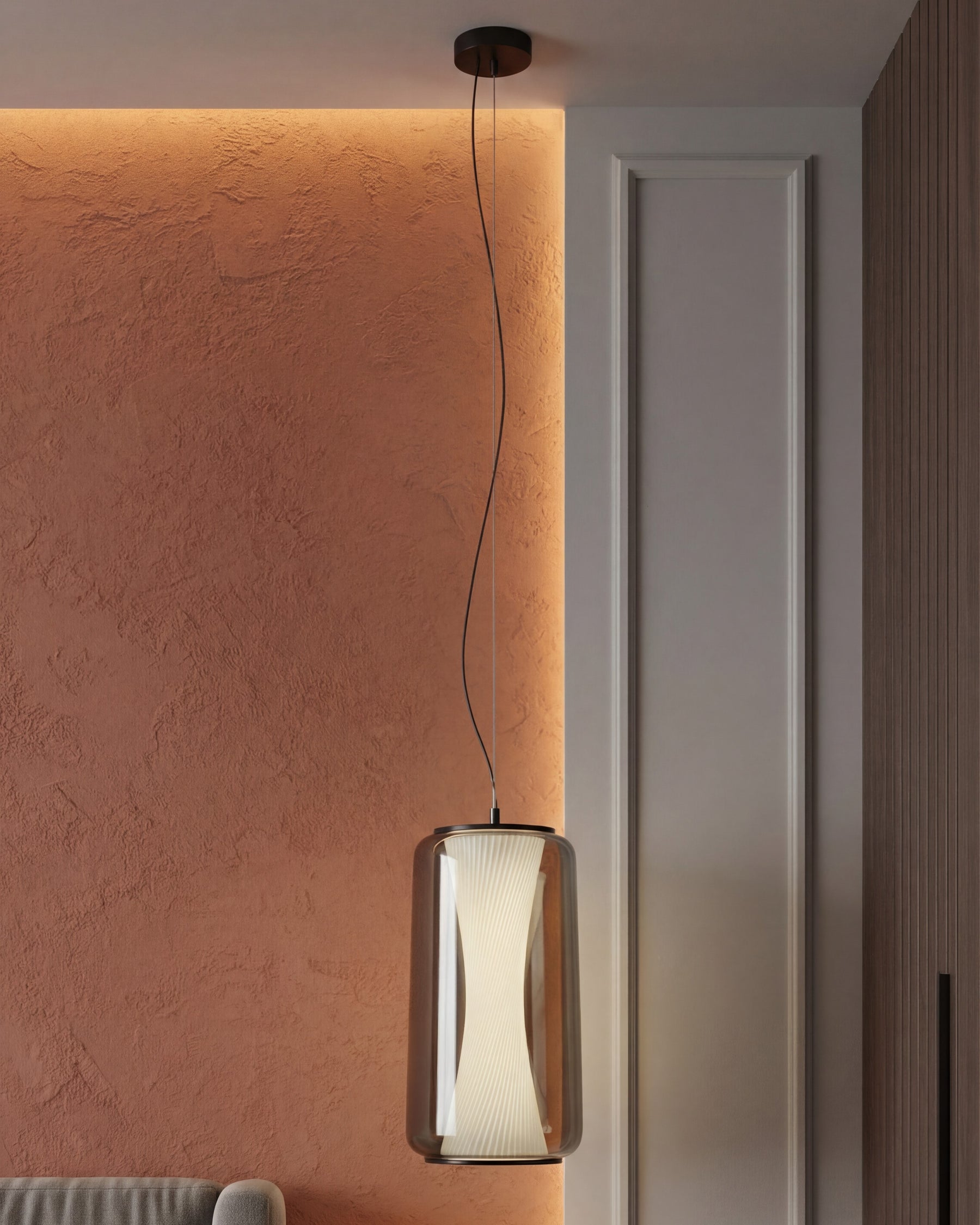 Modern pendant light hanging against a textured wall with a neutral door in the background. 