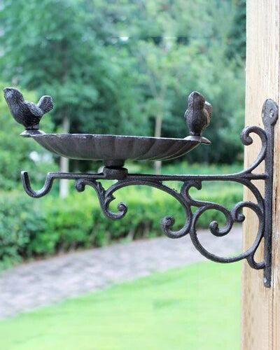 Rustic cast iron hanging bird bath with perching bird design, suitable for traditional garden aesthetics.