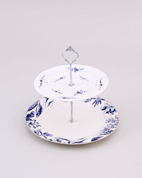 Two-tiered ceramic cake stand with blue floral design on a light gray background 
