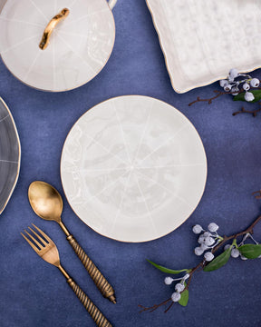 Stylish quarter plate with an embossed white line design displayed with luxury gold cutlery, contrasting on a vivid blue background, for an upscale dining experience.