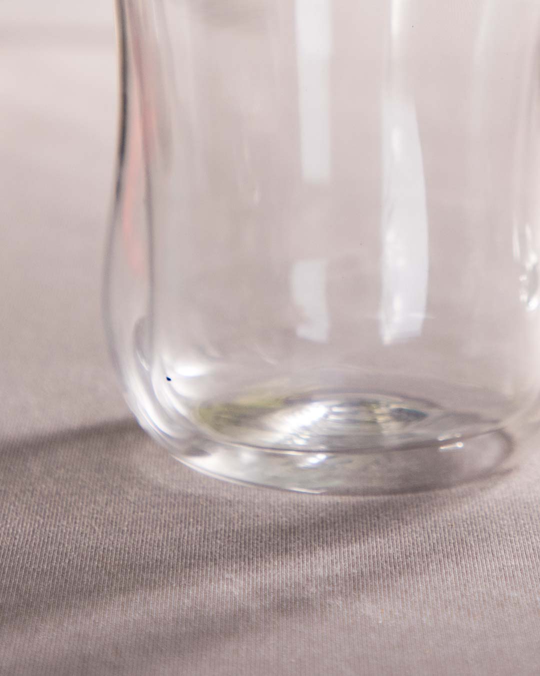Close-up of the double-walled design of a transparent glass tea cup on a textured tablecloth.