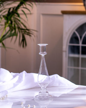 Clear glass candlestick holder on a white tablecloth, enhancing the romantic and sophisticated setting of a dining area.