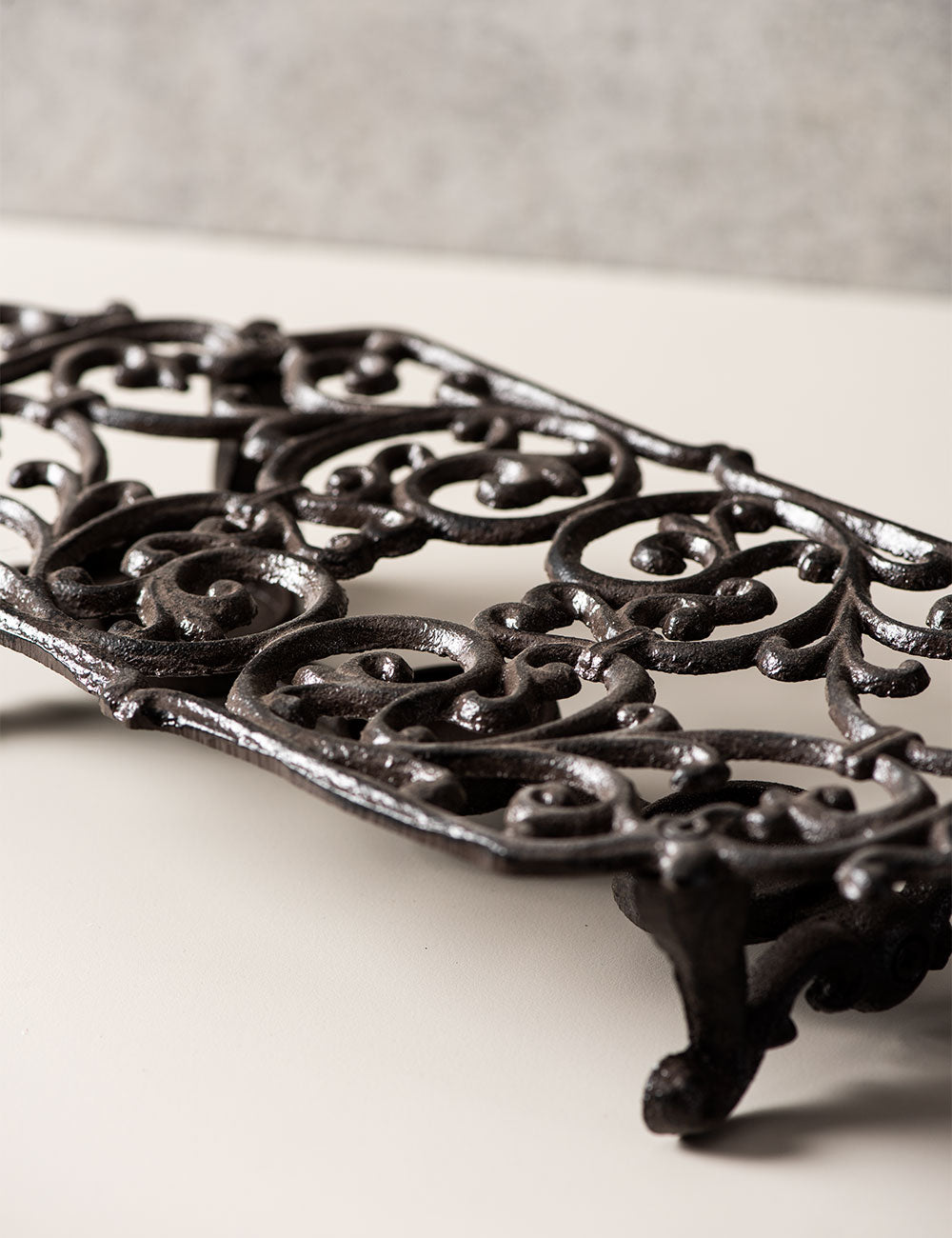 Classic black cast iron dish warmer, side angle showcasing elaborate scroll details. 
