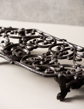 Classic black cast iron dish warmer, side angle showcasing elaborate scroll details. 