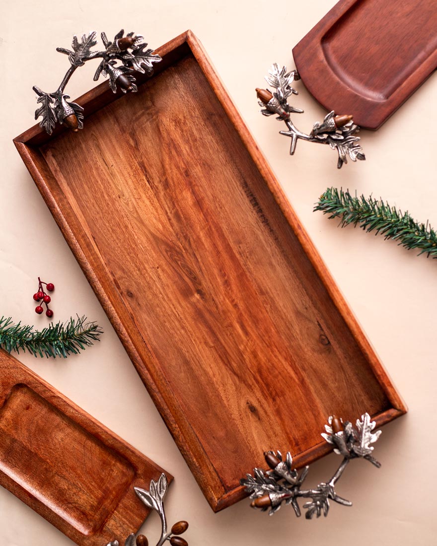 Rustic wooden serving tray with unique acorn and leaf handles, set against a neutral background with festive decorations, embodying a cozy autumnal vibe.
